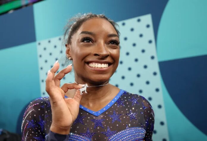 Simone Biles poses with a necklace in the likeness of a goat after winning the women’s all-around final on day six of the Olympic Games Paris 2024 at Bercy Arena